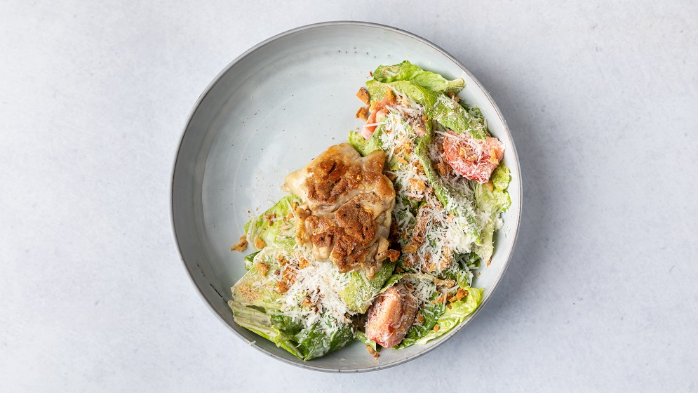 Grilled chicken thighs salad with, romaine lettuce, Caesar sauce, tomatoes, Parmesan cheese and onion chips