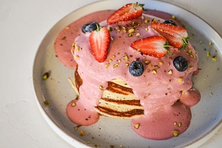 Pancakes with strawberry sauce, fresh berries and pistachios