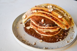 Pancakes with caramelized banana, salted caramel, chocolate sauce and hazelnuts