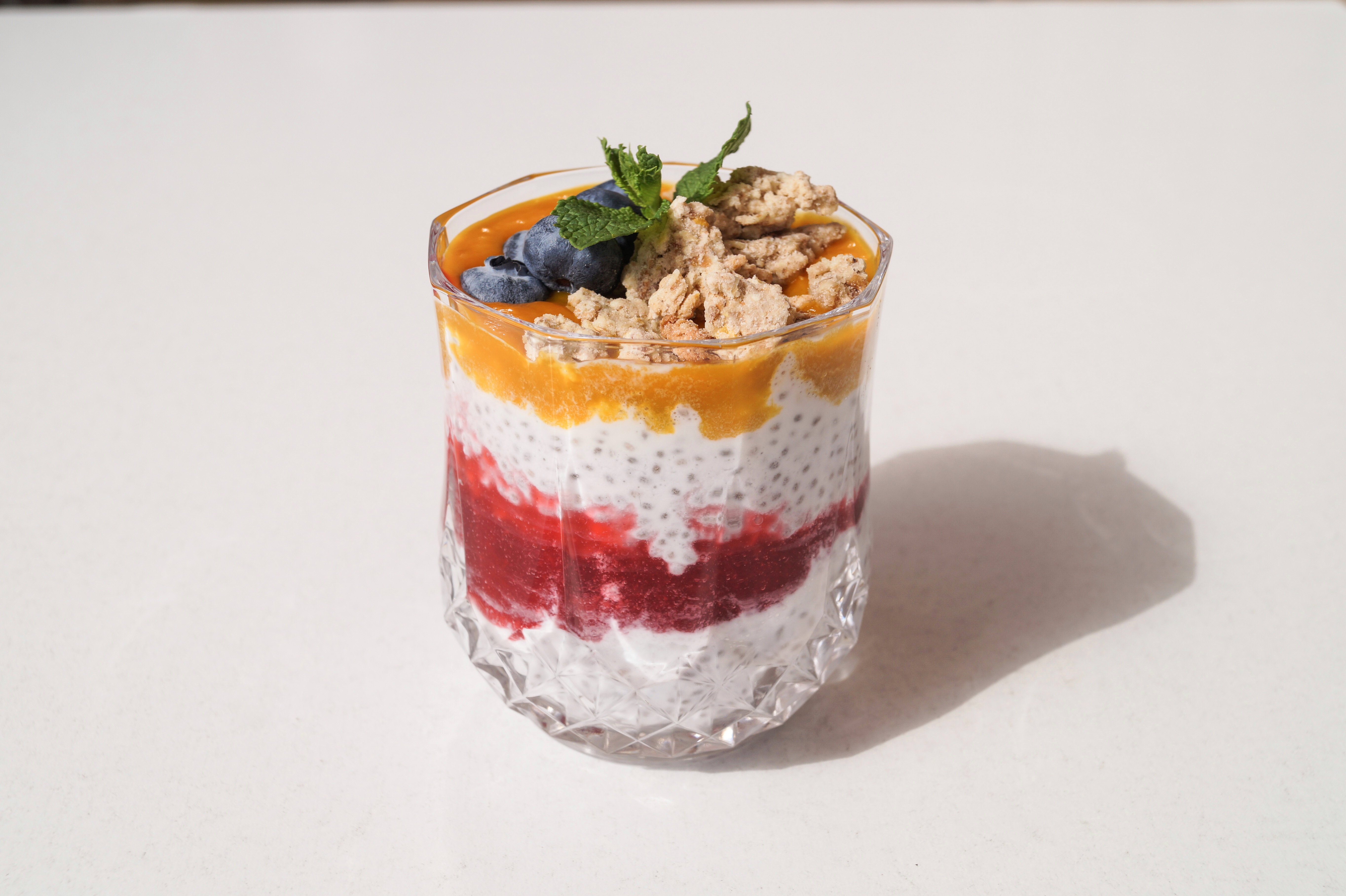 Chia pudding with coconut milk with mango puree, crunch crumble, strawberry-raspberry puree and blueberries