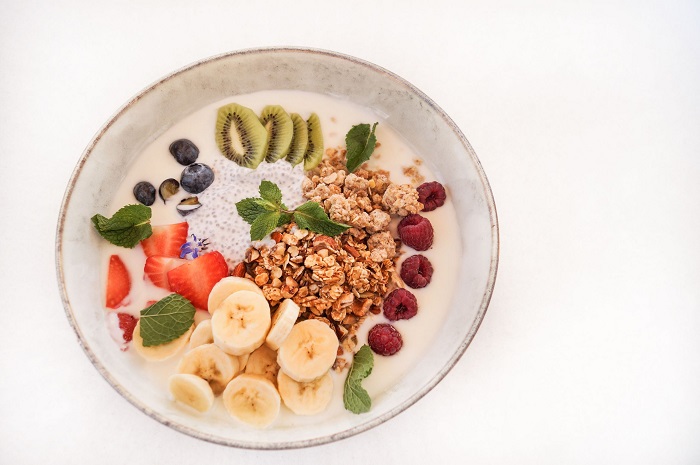 Granola bowl with yoghurt, chia pudding, banana, kiwi and fresh berries