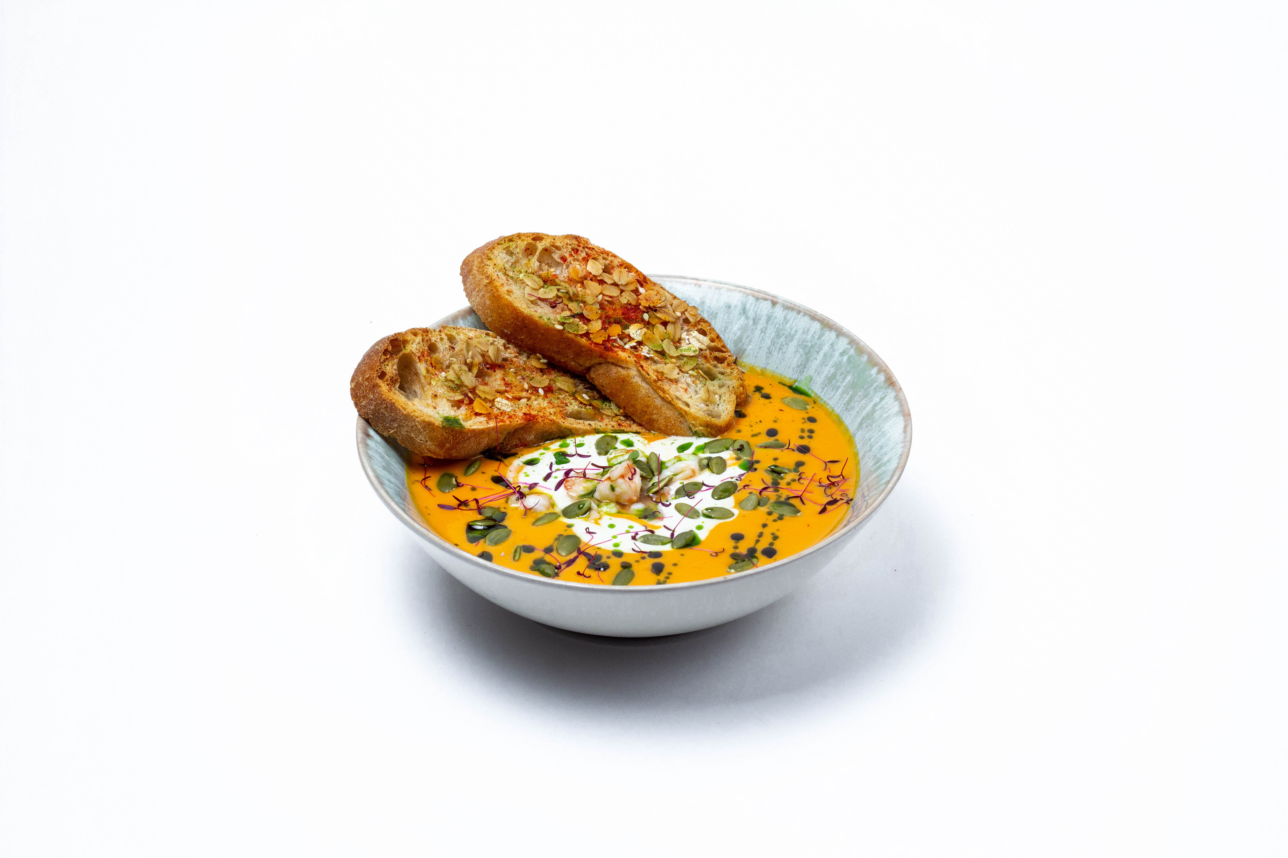 Pumpkin soup with tiger prawns in fragrant herbs, Stracciatella cheese, ciabatta croutons and pumpkin seeds