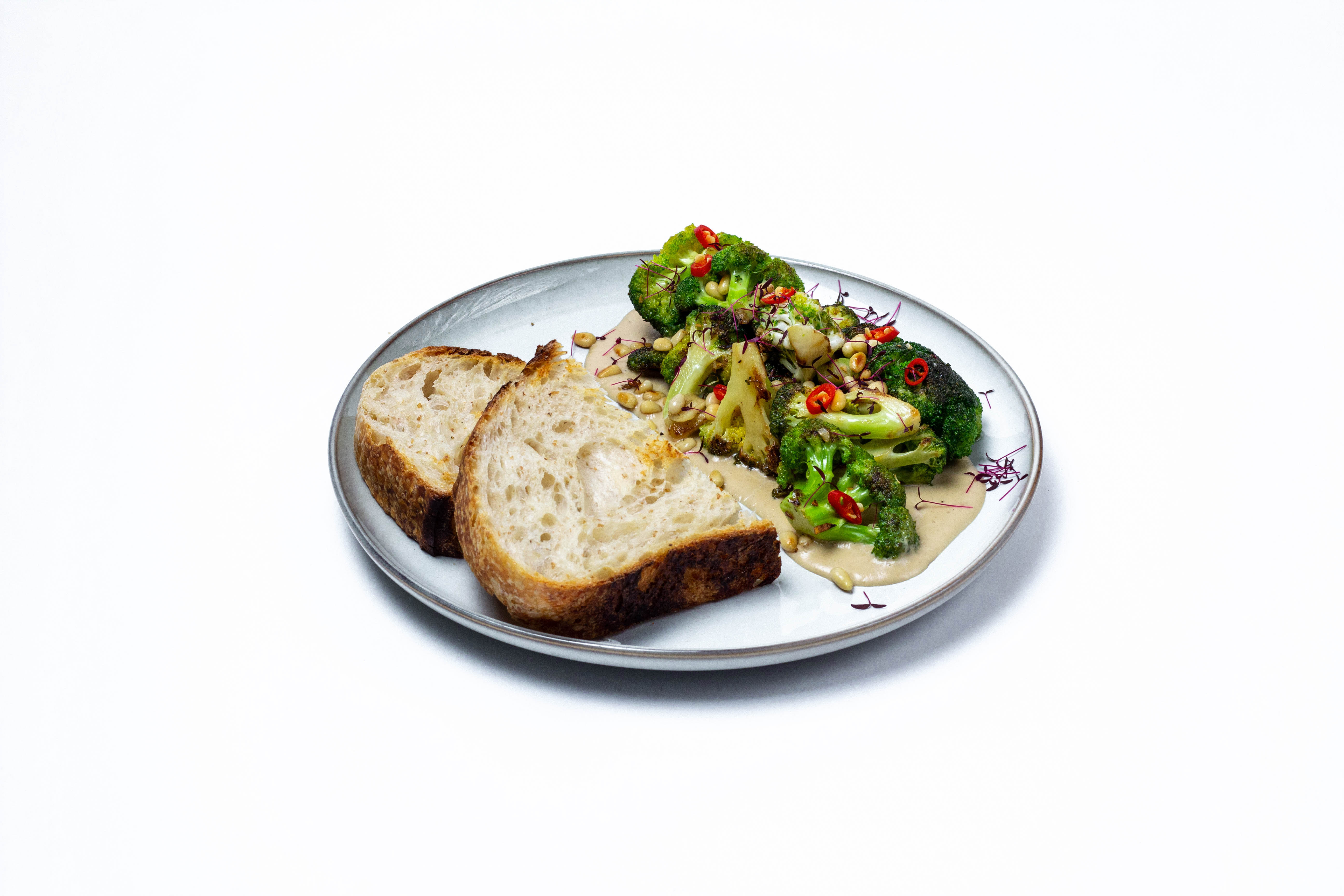 Broccoli with pine nuts, chili flakes in tahini sauce and sourdough bread tartin
