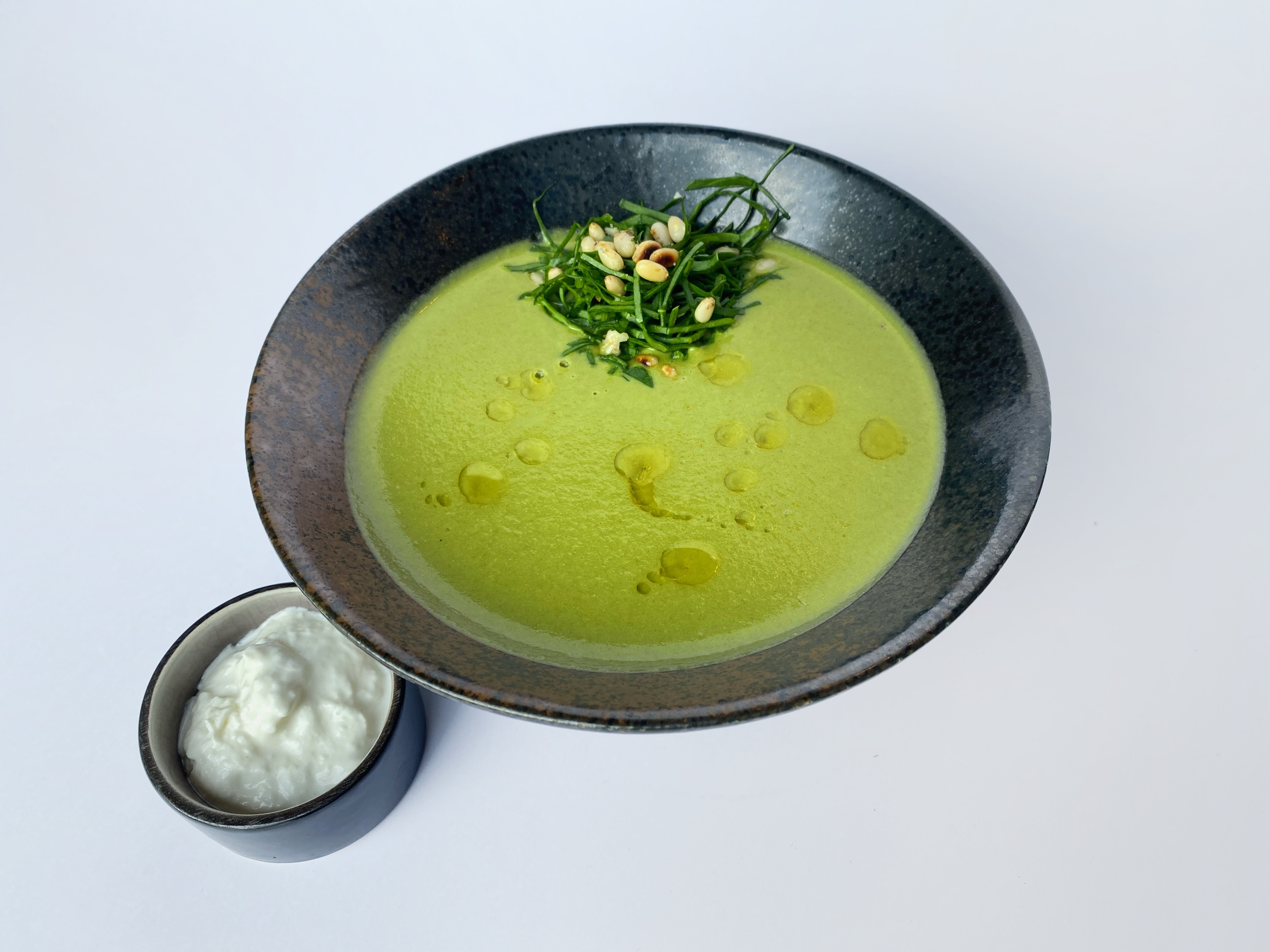 Green cream soup of zucchini, spinach, Kenyan beans, green peas with stracciatella and pine nuts<br>