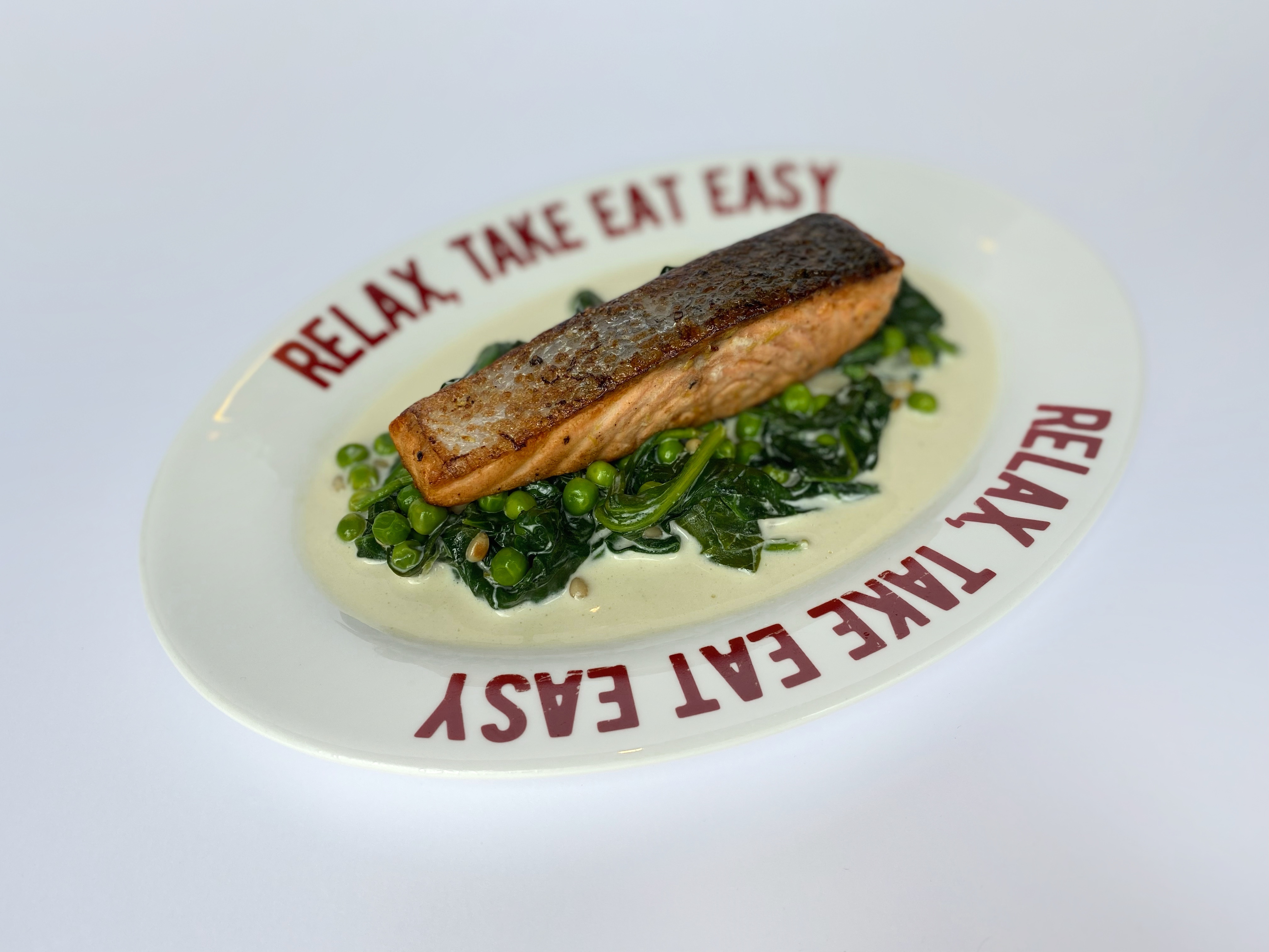 Salmon steak with creamed spinach, green peas and pine nuts<br>